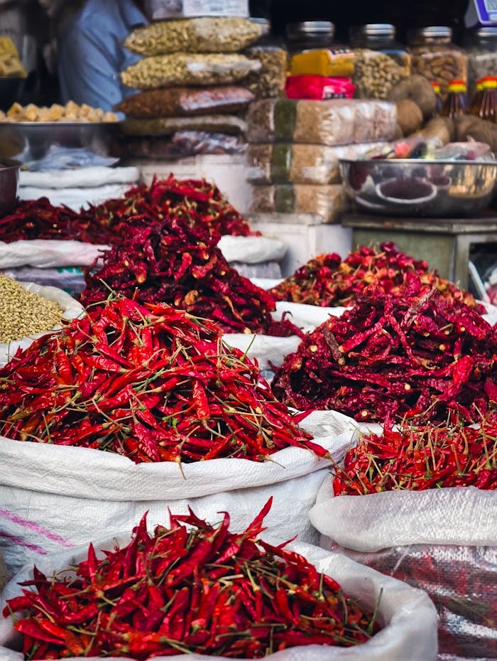 Bags of dried red chilies on display in a bustling spice market, showcasing vibrant colors.